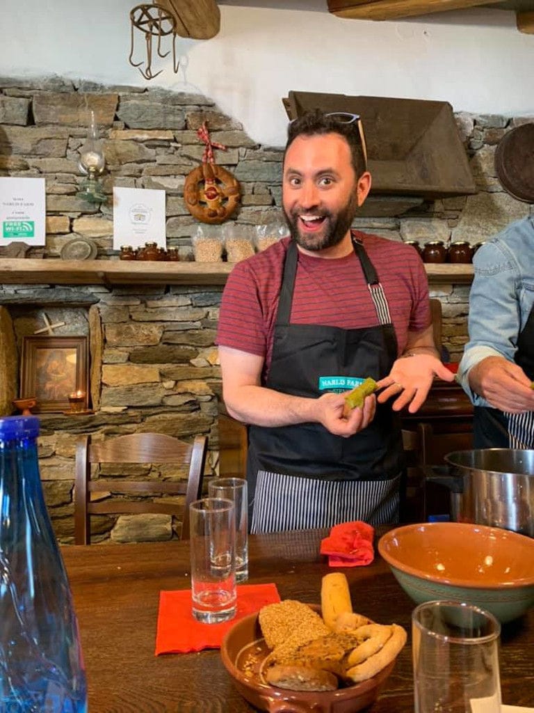 man smiling happily at the camera and holding a piece of bread at 'Narlis Farm' kitchen